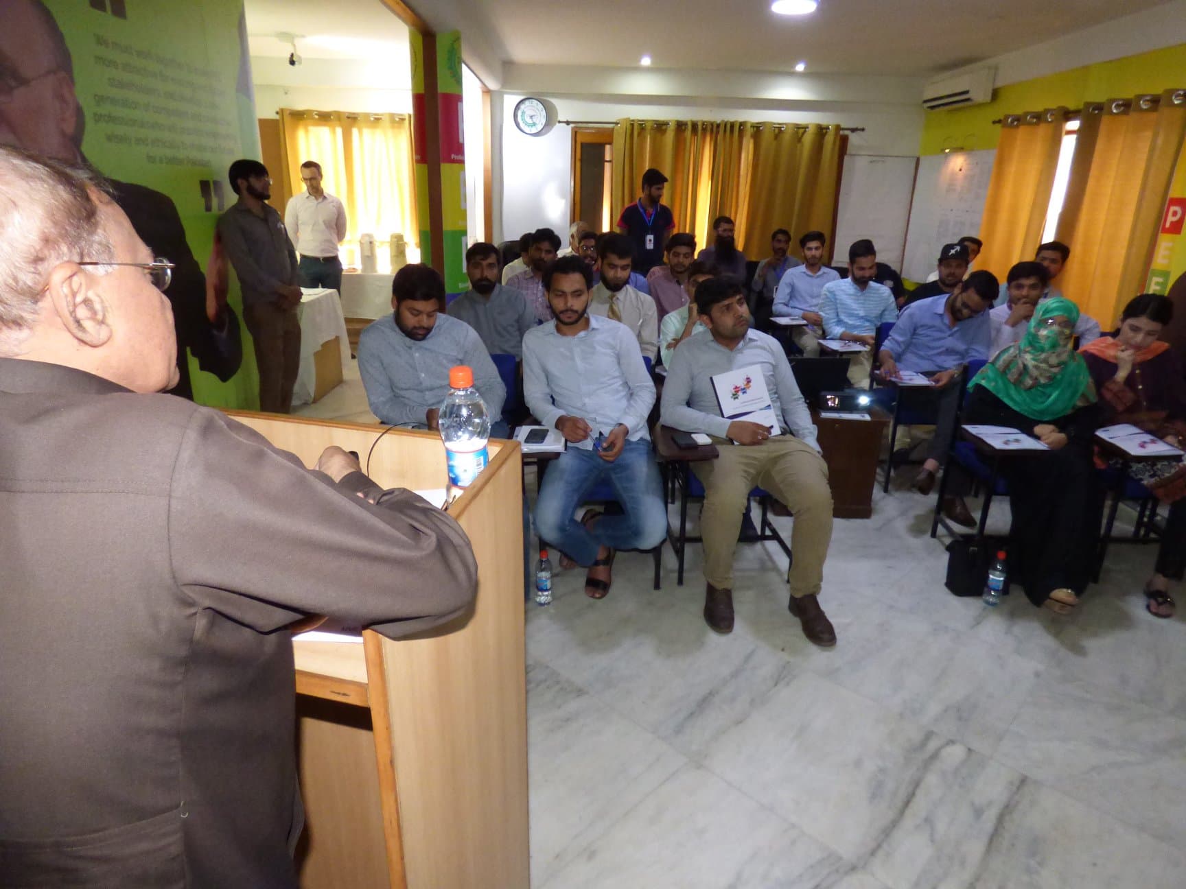 A trainer addresses young engineers seated in a seminar room during the PEG training on the sustainable power bridge.