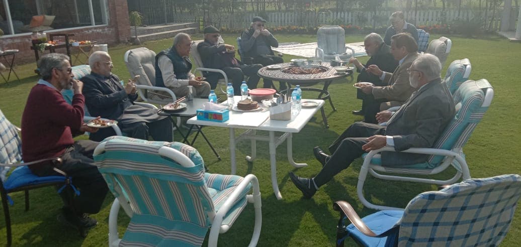 Members of PEG's Core Committee seated around a table on a lawn during their meeting.