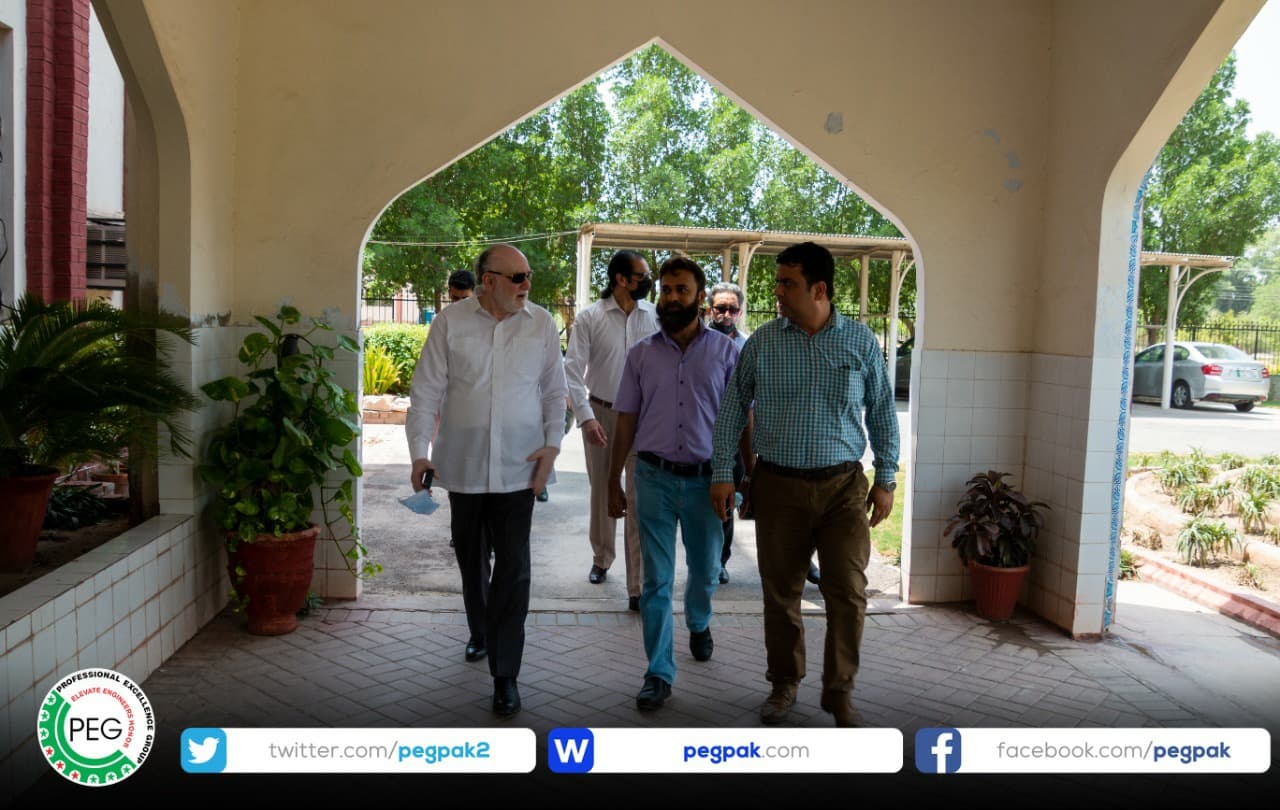 Engr. Waseem Nazir walking through an arched walkway with colleagues at Bahauddin Zakariya University, Multan.